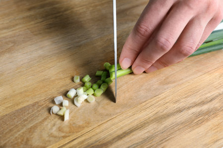 Woman cutting green spring onion on wooden board, closeupの写真素材