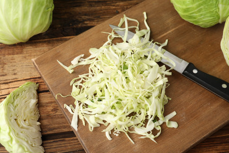 Chopped ripe cabbage and knife on wooden board, closeupの写真素材