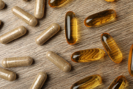 Various dietary supplements capsules on wooden table, flat lay