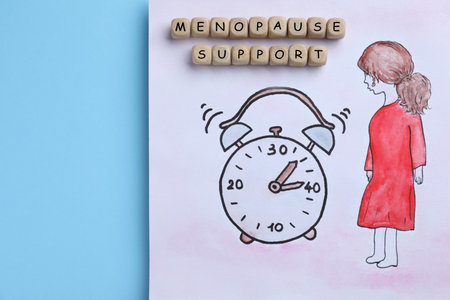 Drawing of woman figure near alarm clock and wooden cubes with words Menopause Symptoms on light blue background, top viewの写真素材