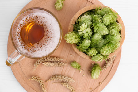 Mug with beer, fresh hops and ears of wheat on white wooden table, top viewの写真素材