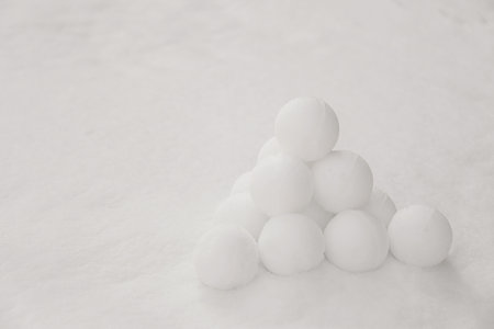 Pyramid of perfect snowballs on snow outdoors. Space for text
