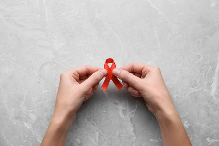 Woman holding red awareness ribbon at light gray marble table, top view. World AIDS disease dayの写真素材