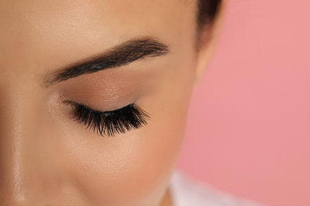 Beautiful young woman with long eyelashes on pink background, closeup. Space for textの写真素材