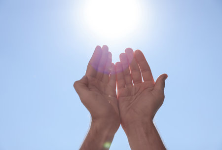 Man reaching hands to blue sky outdoors on sunny day, closeupの写真素材