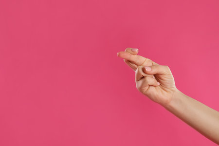 Woman holding fingers crossed on pink background, closeup with space for text. good luck superstitionの写真素材