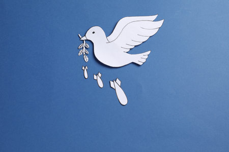 White paper dove with olive branch and bombs on blue background, flat layの写真素材