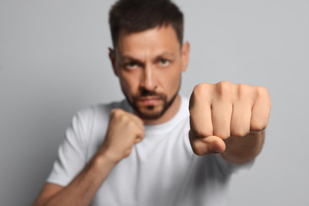 Man throwing punch against gray background, focus on fist. Space for textの写真素材