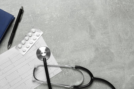 Flat lay composition with cardiogram report and stethoscope on gray background, space for textの写真素材