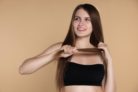 Young woman with strong healthy hair on beige backgroundの写真素材