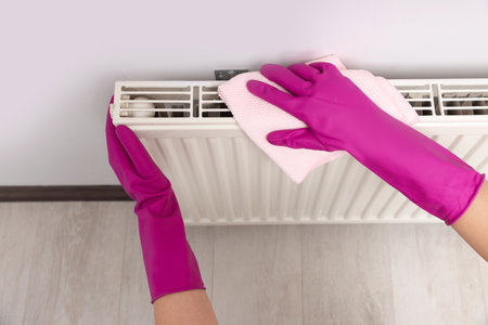 Woman cleaning white radiator with rag indoors, above viewの写真素材