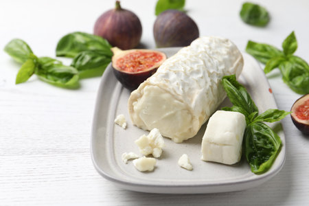 Delicious goat cheese with basil and figs on white wooden tableの写真素材