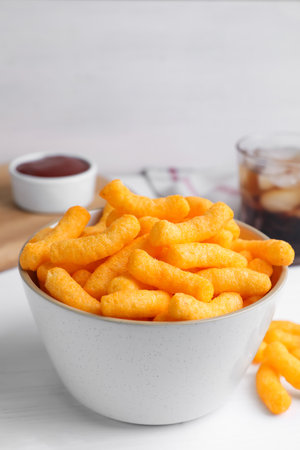 Crunchy cheesy corn snack in bowl on white wooden table, closeupの写真素材