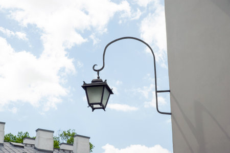 Vintage street lamp on wall of building against blue sky, low angle viewの写真素材