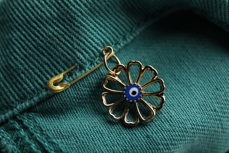 Evil eye safety pin on denim clothing, closeupの写真素材