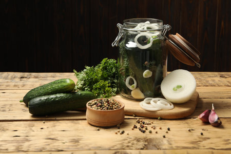 Pickling jar with fresh ripe cucumbers and spices on wooden tableの写真素材