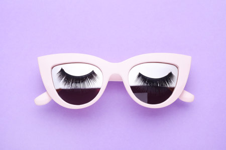 Sunglasses with false eyelashes on violet background, top viewの写真素材