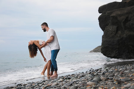 Happy young couple having fun on the beach near the sea. Space for text