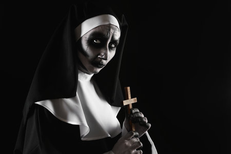Scary devilish nun with cross on black background, space for text. halloween party lookの写真素材