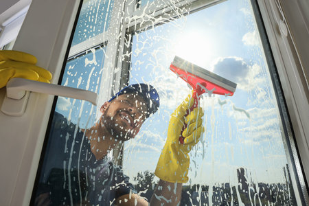Man cleaning glass with squeegee indoors, low angle viewの写真素材