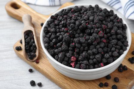 Bowl and scoop with dried blueberries on white wooden tableの写真素材
