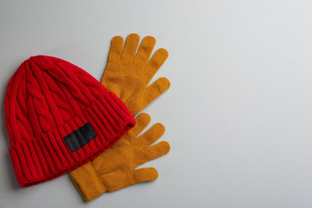 Woolen gloves and hat on light gray background, flat lay. Space for textの写真素材