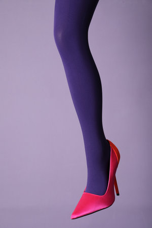 Woman wearing bright tights and high heel shoe on violet background, closeupの写真素材