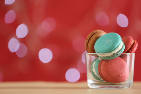 Delicious macarons in bowl on table against blurred background, closeup. Space for textの写真素材