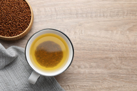 Buckwheat tea in cup and bowl with granules on wooden table, flat lay. Space for textの写真素材