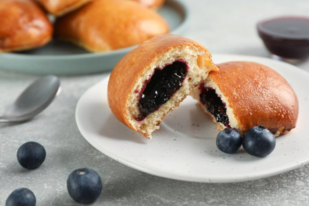 Delicious baked patties with jam and blueberries on light gray table, closeupの写真素材