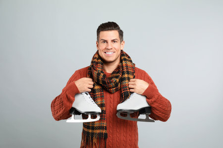 Happy man with ice skates on gray backgroundの写真素材