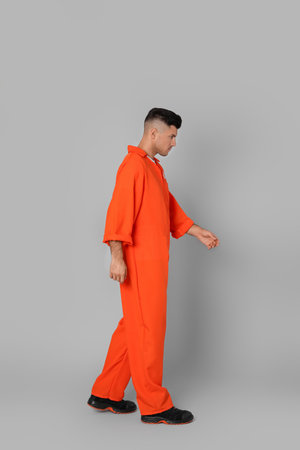 Prisoner in orange jumpsuit on gray backgroundの写真素材