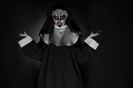 Portrait of scary devilish nun on black background. halloween party look