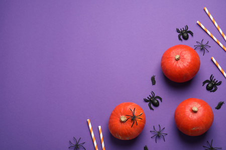 Flat lay composition with pumpkins, straws and spiders on purple background, space for text. halloween decorの写真素材