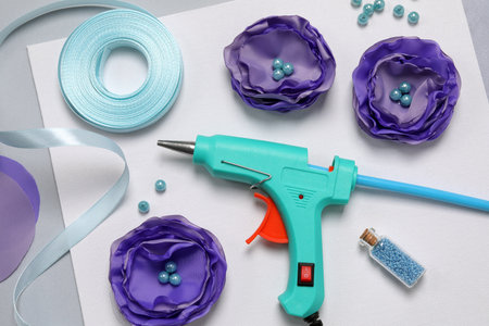 Hot glue gun, textile flowers and handicraft materials on color background, flat layの写真素材