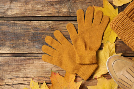 Flat lay composition with stylish woolen gloves and dry leaves on wooden table. Space for textの写真素材