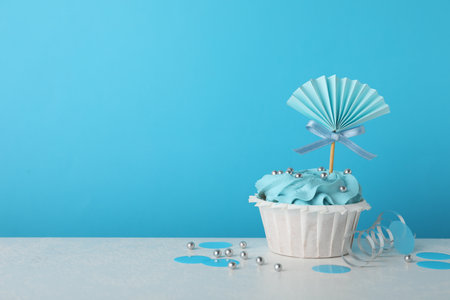 Baby shower cupcake with topper on white table against light blue background, space for textの写真素材