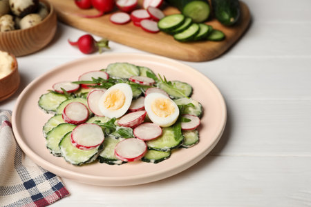 Tasty fresh salad with cucumber and ingredients on white wooden tableの写真素材