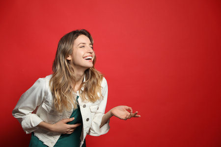 Cheerful young woman laughing on red background. Space for textの写真素材