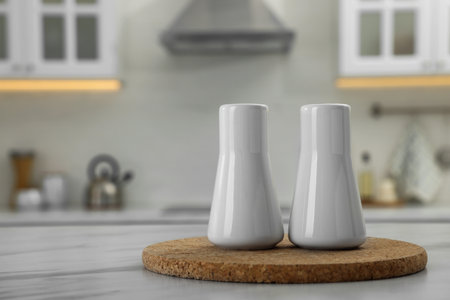Ceramic salt and pepper shakers on white marble table in kitchen. Space for textの写真素材