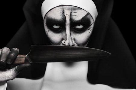 Scary devilish nun with knife on black background, closeup. halloween party lookの写真素材