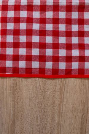 Checkered picnic cloth on wooden table, top view. Space for text