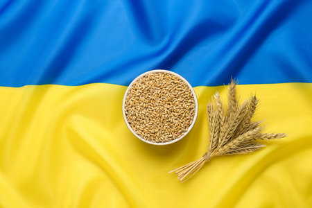 Bowl of wheat grains and ears on national Ukrainian flag, flat layの写真素材