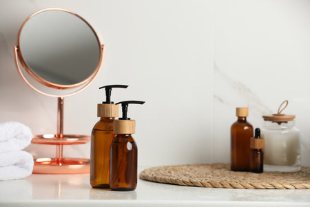 Glass bottles with dispenser caps on table in bathroomの写真素材