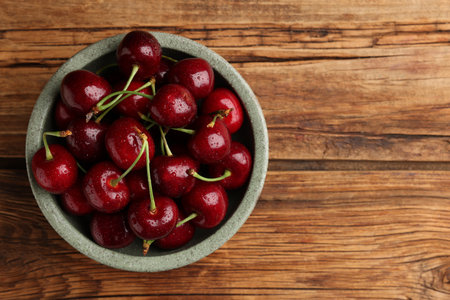 Bowl with ripe sweet cherries on wooden table, top view. Space for textの写真素材