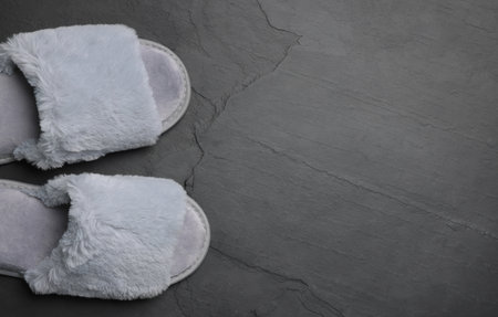 Pair of soft slippers on dark gray floor, top view, closeup. Space for textの写真素材