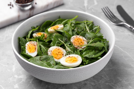 Delicious salad with boiled eggs and herbs in bowl on light gray marble table, closeupの写真素材