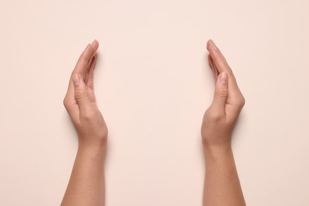 Woman holding on pale pink background, closeup of hands. Space for textの写真素材