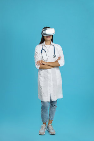 Female doctor using virtual reality headset on light blue backgroundの写真素材