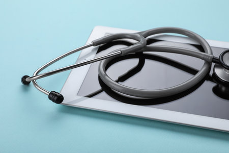 Computer tablet and stethoscope on turquoise background, closeupの写真素材